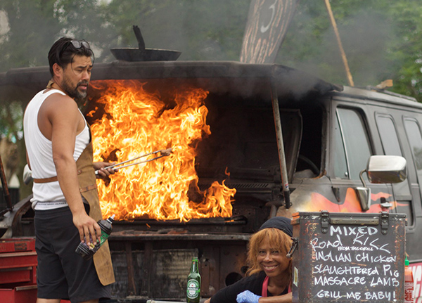 Man barbecuing from a food truck with a grill in the hood of an old van