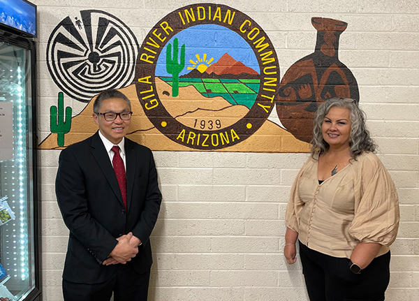 Man and woman standing next to a wall with a Gila River Indian Community logo
