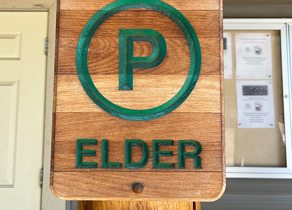 A wood sign on a building for Elder parking