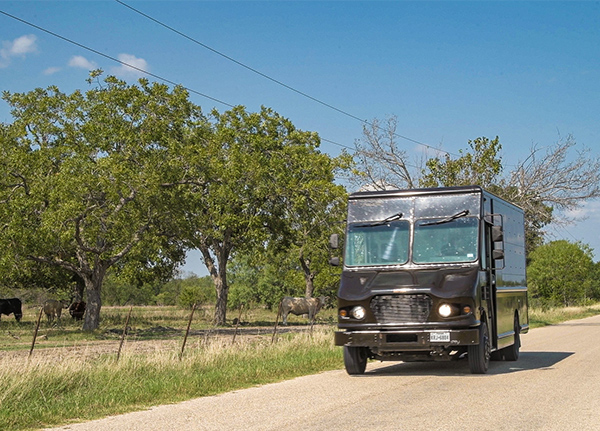 Delivery truck driving down a dirt road