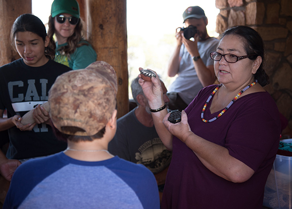 Woman standing in front of a small group holding and talking about rocks