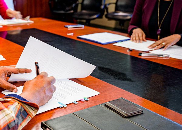Person sitting at boardroom desk signing papers
