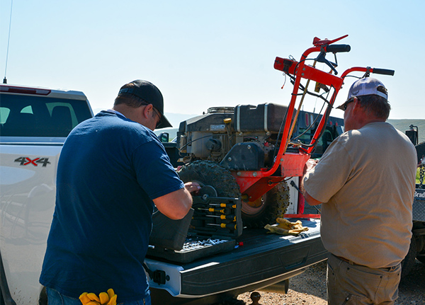 Two men loading lawn machinery into the back of a truck