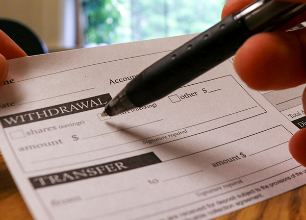 Person filling out a deposit/withdrawal bank slip
