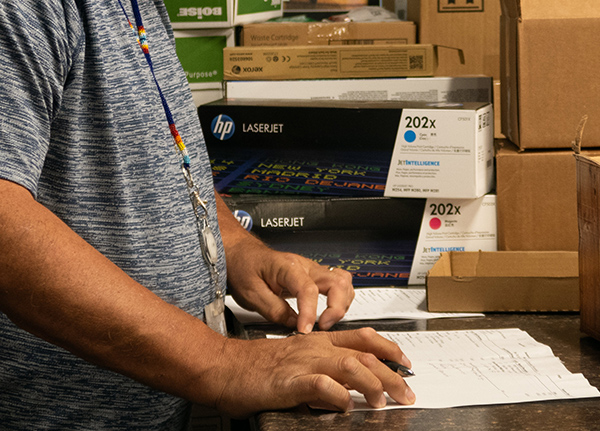 Person standing at a desk with a paper on the desktop in front of them