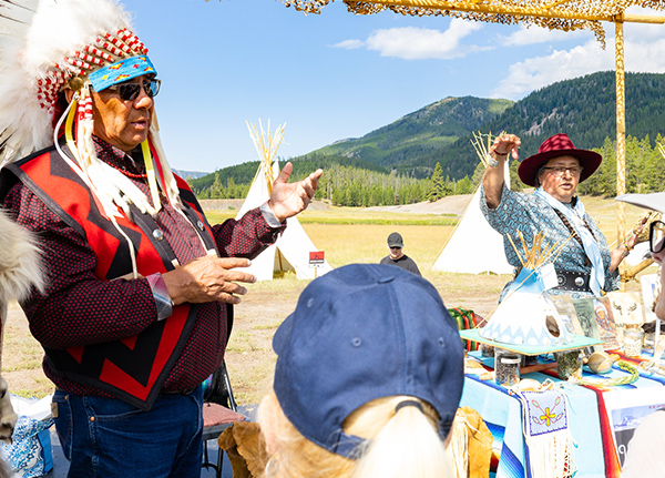 Man wearing a traditional tribal wardrobe talking to a small group of people