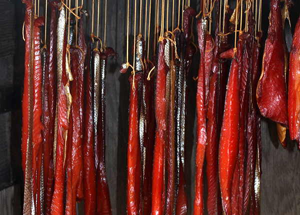 Salmon hanging from strings getting smoked