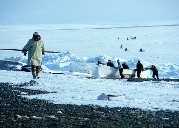 Eskimo fishermen walking across a snowy landscape