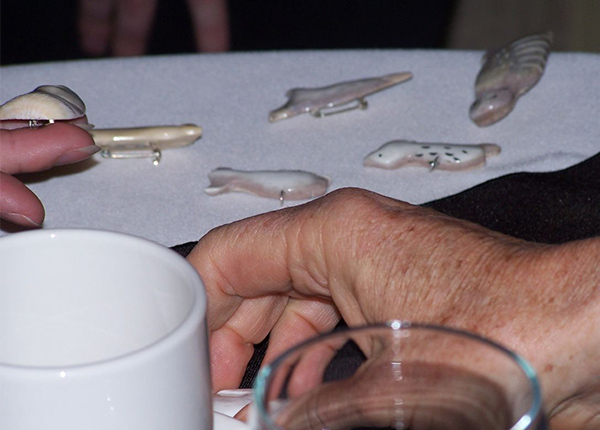 A hand next to carved pins and pendants