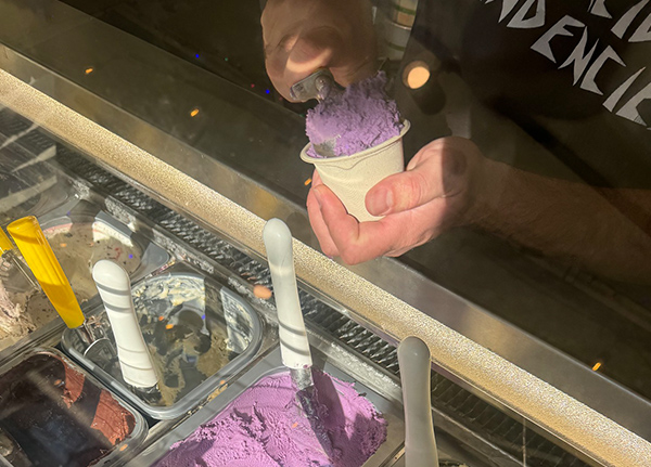 Hand scooping ice cream into a cup